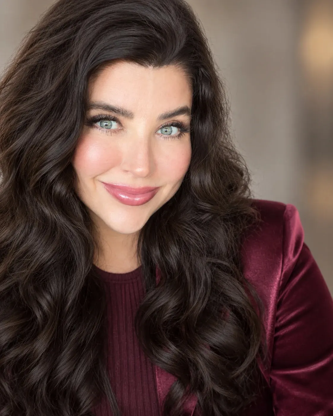 Portrait of Christy in a burgundy velvet blazer, dark hair loose over her shoulders.