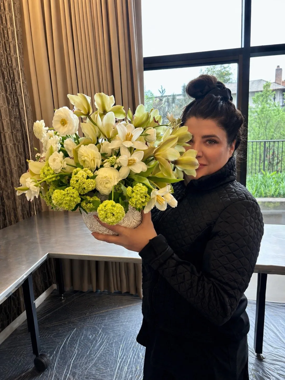 Christy holding a sculptural white and green arrangement of tulips, lilies and hydrangea.