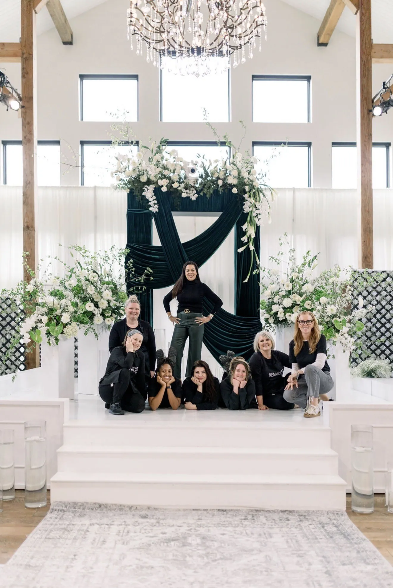 The floral team gathered on a velvet-draped altar set beneath white installations and a crystal chandelier.