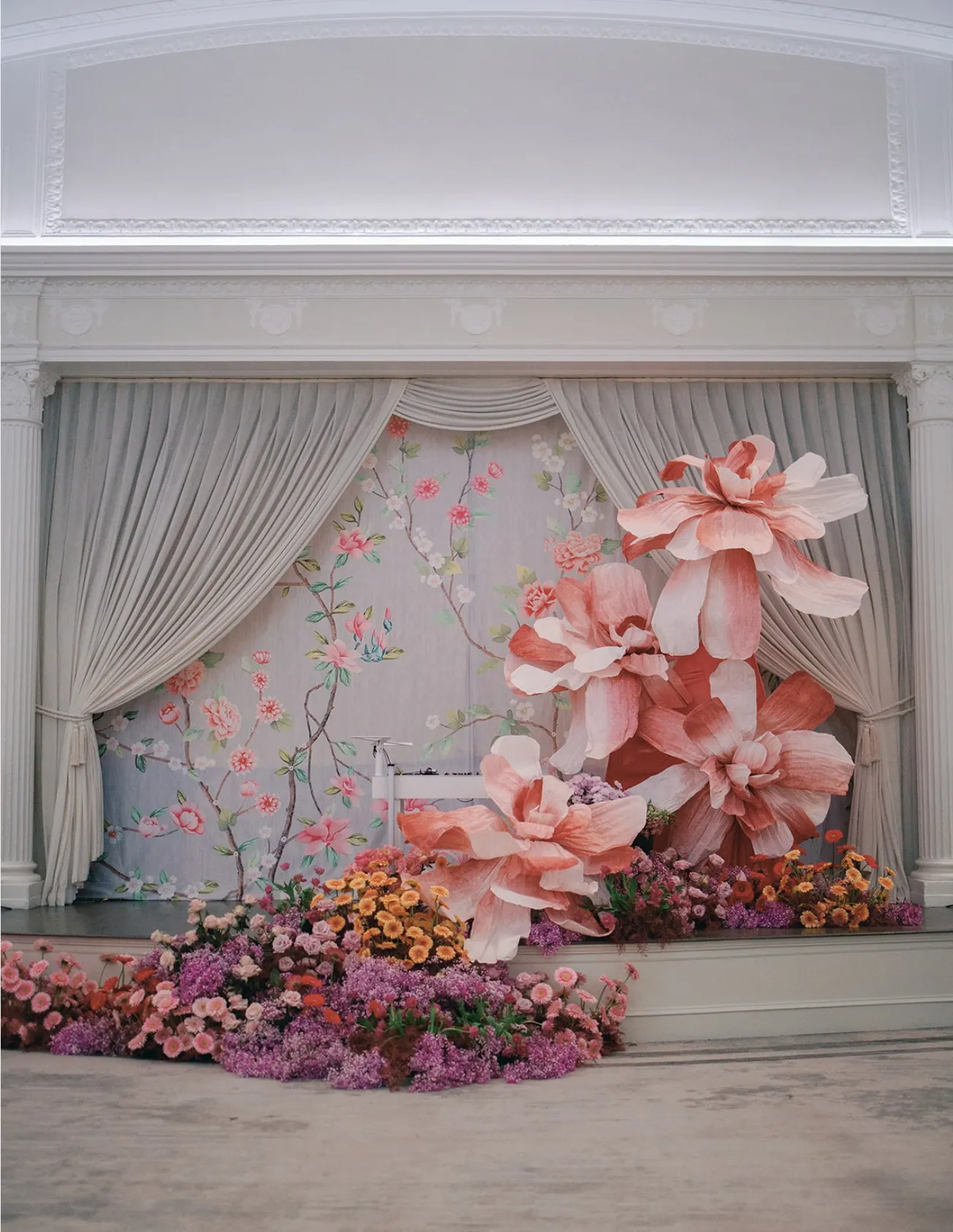 Large-scale paper floral installation framing an event stage.