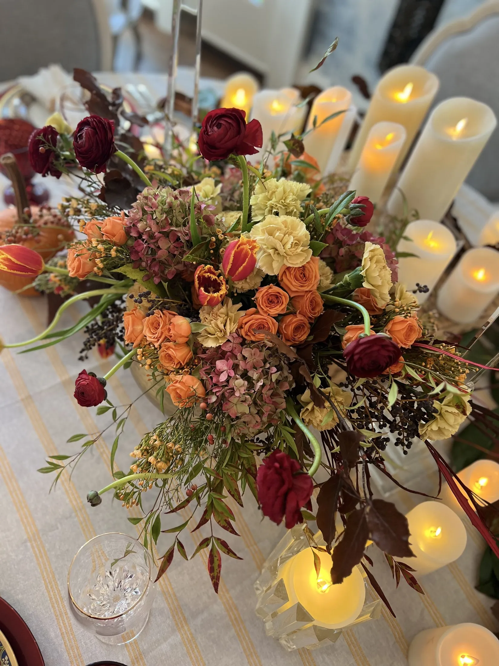 Autumn arrangement in rust and burgundy glowing over votive candles.