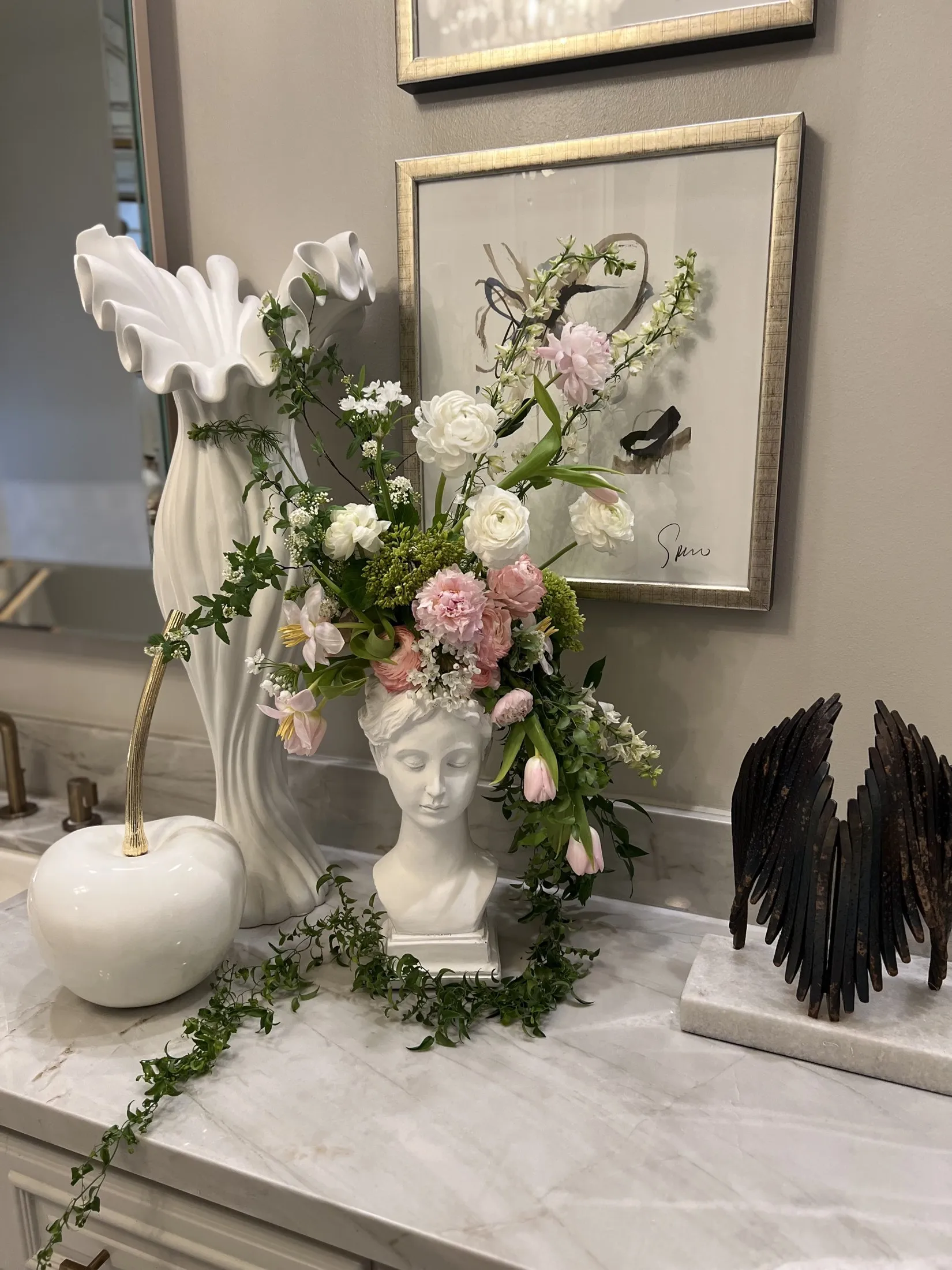 White bust and trailing garland styled on a marble console.