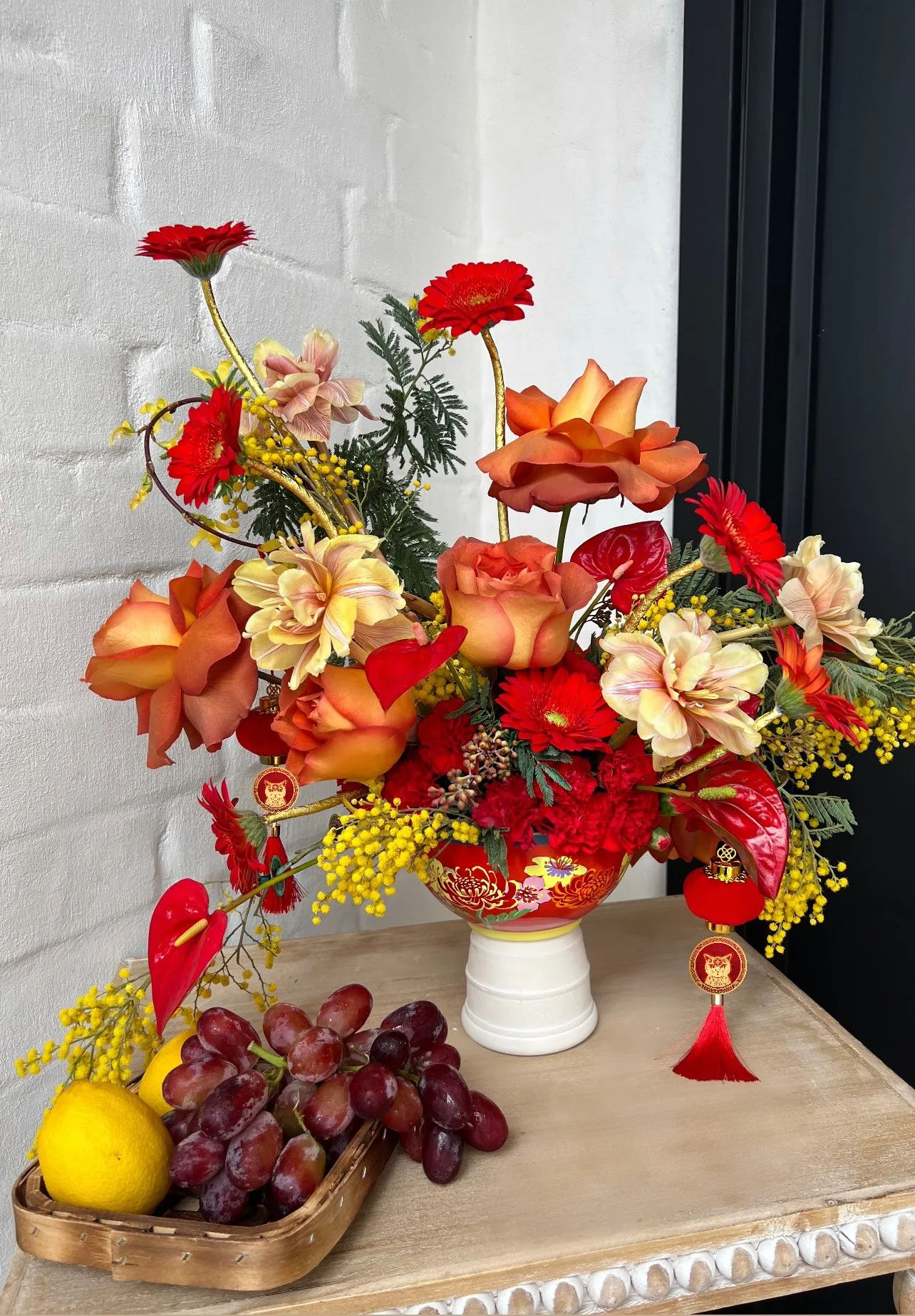 Red, coral and cream arrangement with fruit on an entry console.