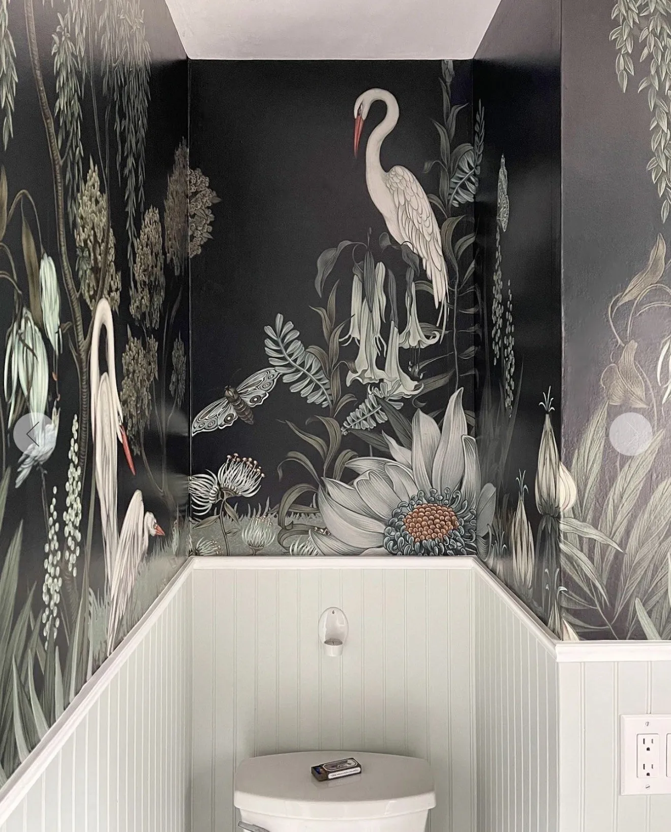 Red roses and greenery styled on a marble counter beneath a heron mural.