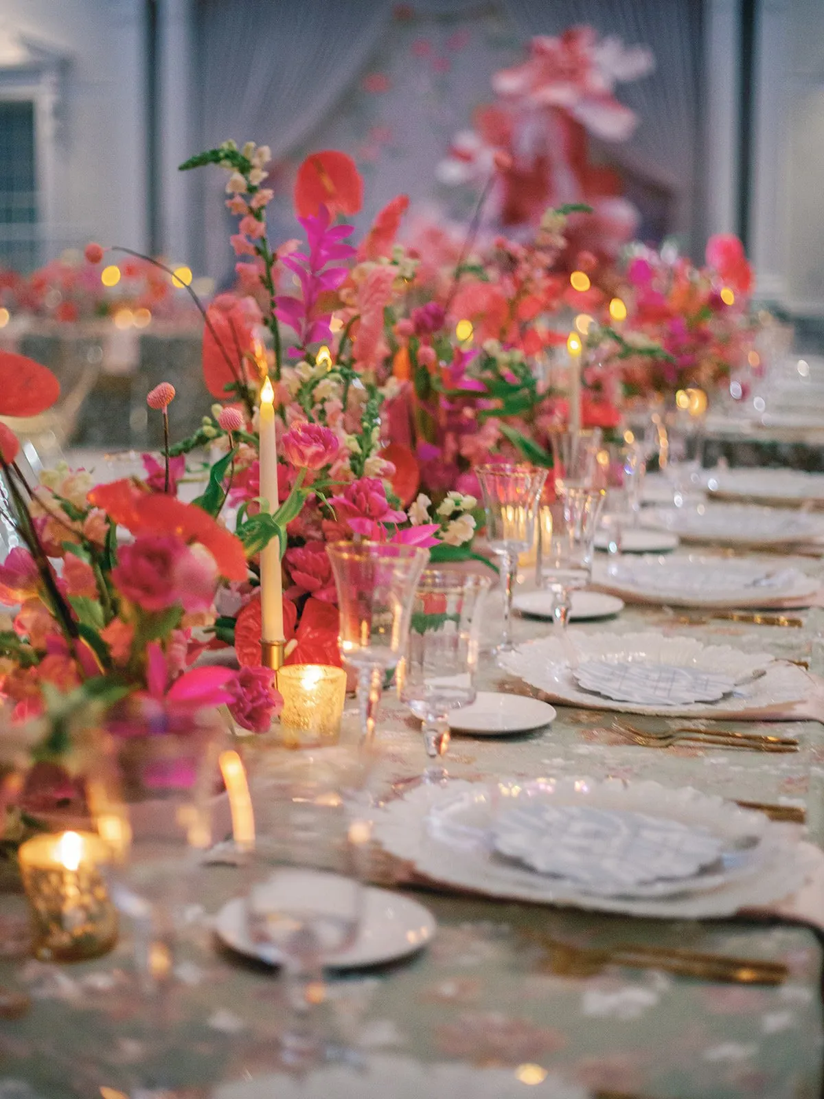 Candlelit tablescape with towering pink and red florals down the table run.