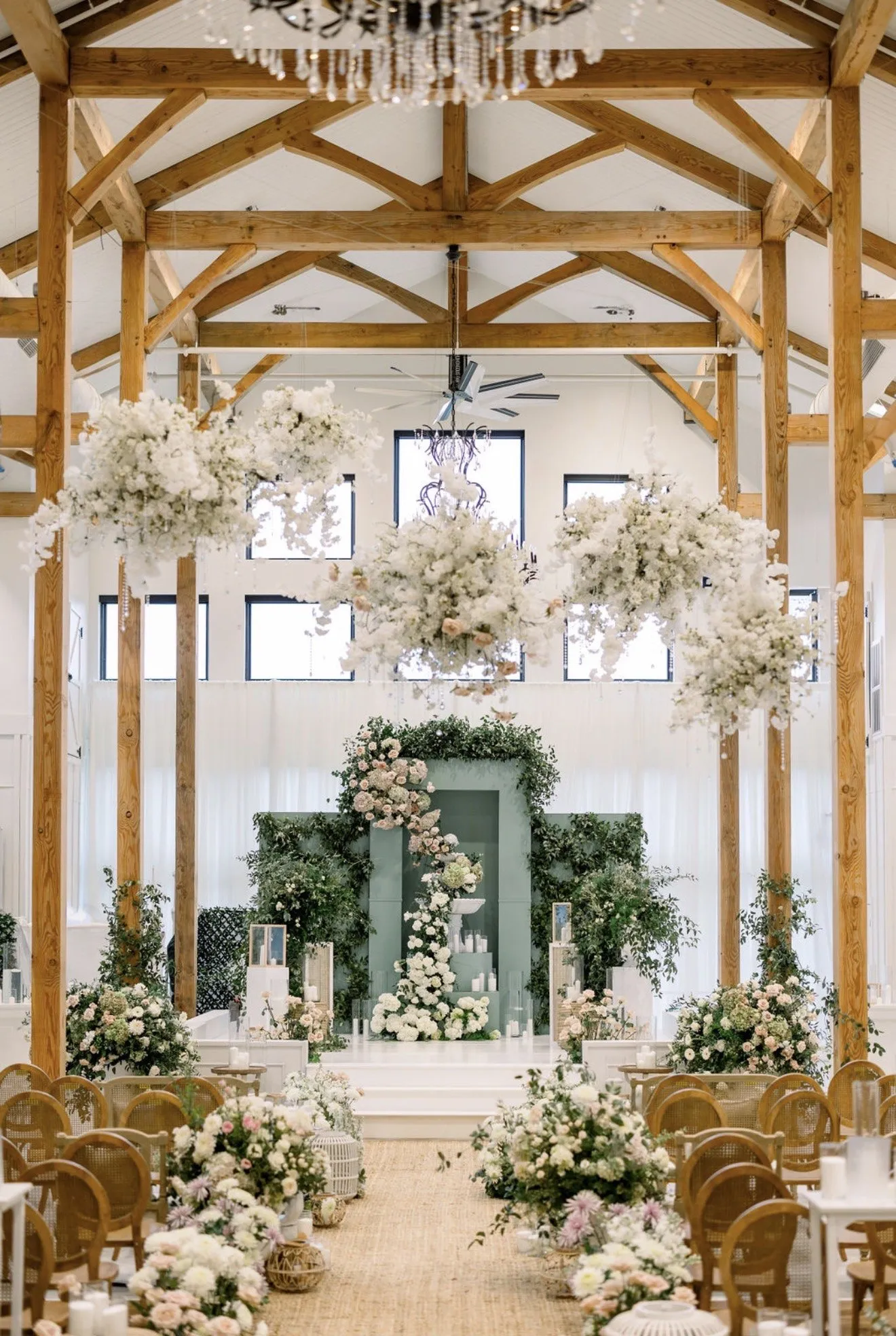 Timber-frame ceremony room dressed in white florals and greenery.