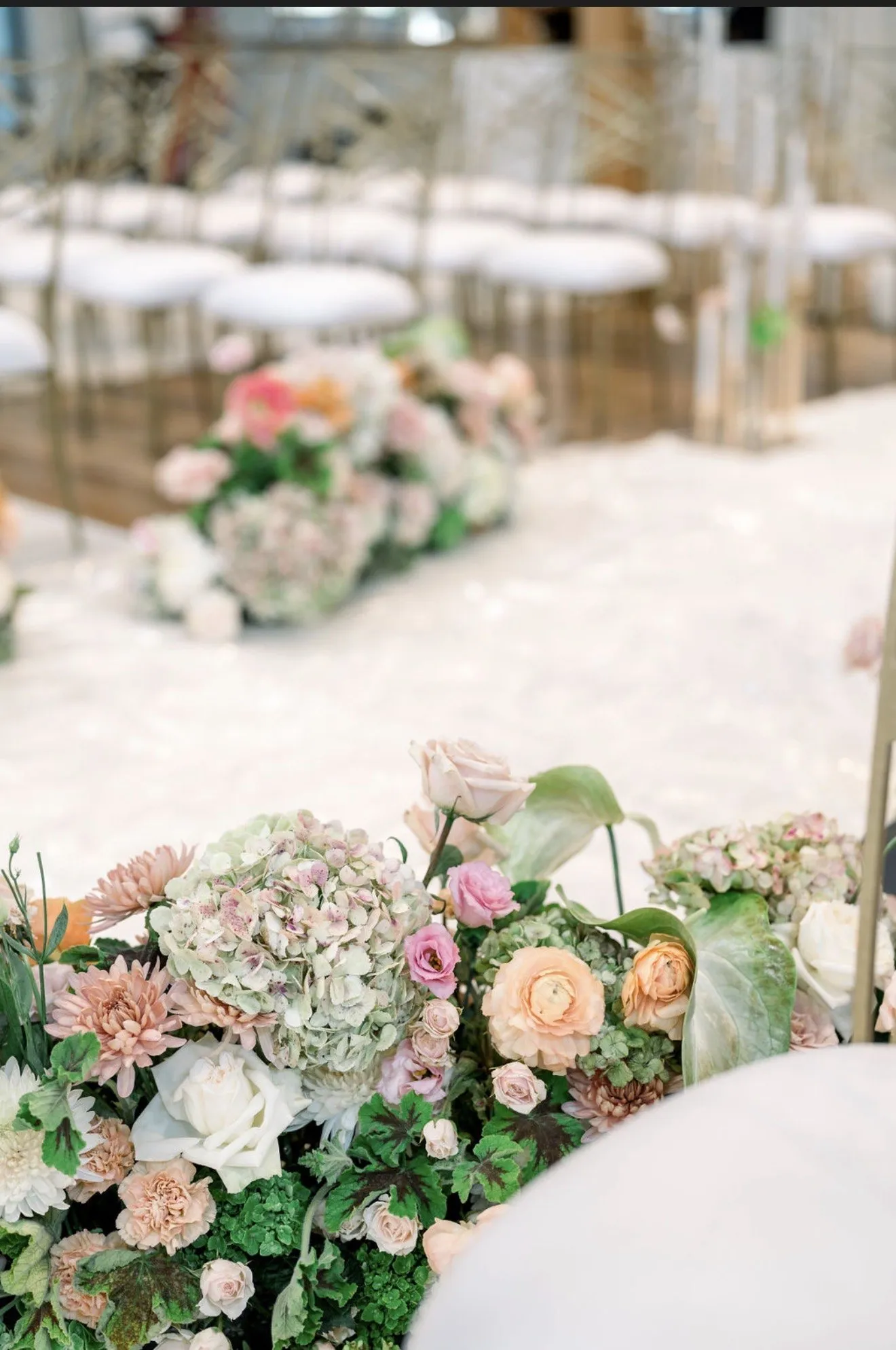 Blush and green aisle florals in soft focus.