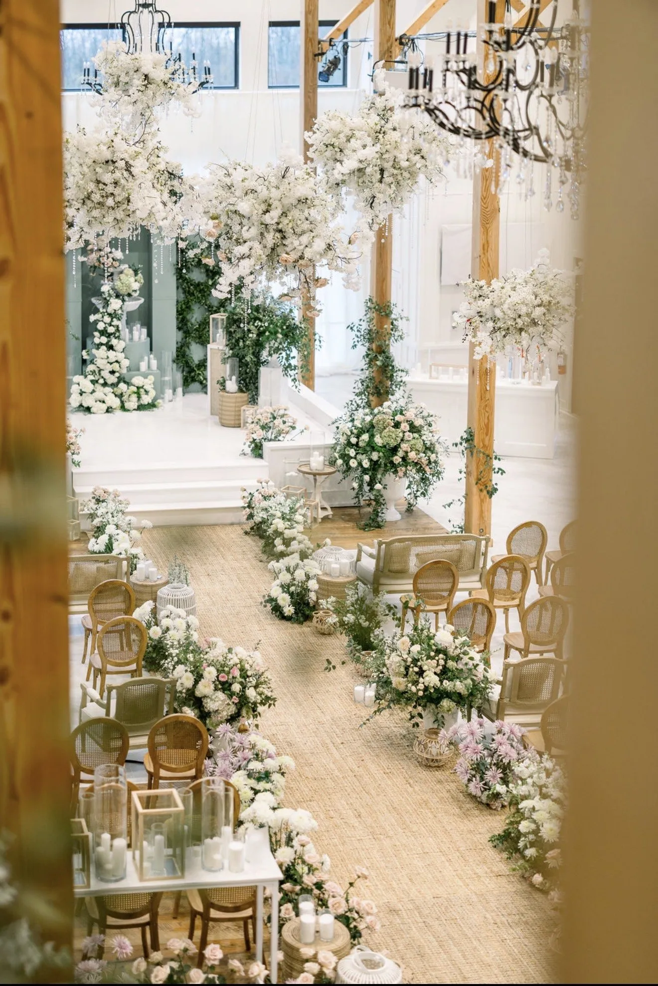 Candlelit aisle with pedestal arrangements and hanging greenery.