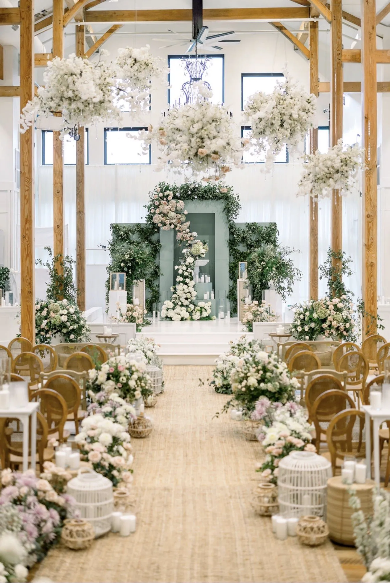 Ceremony aisle lined with white and green arrangements toward the altar.