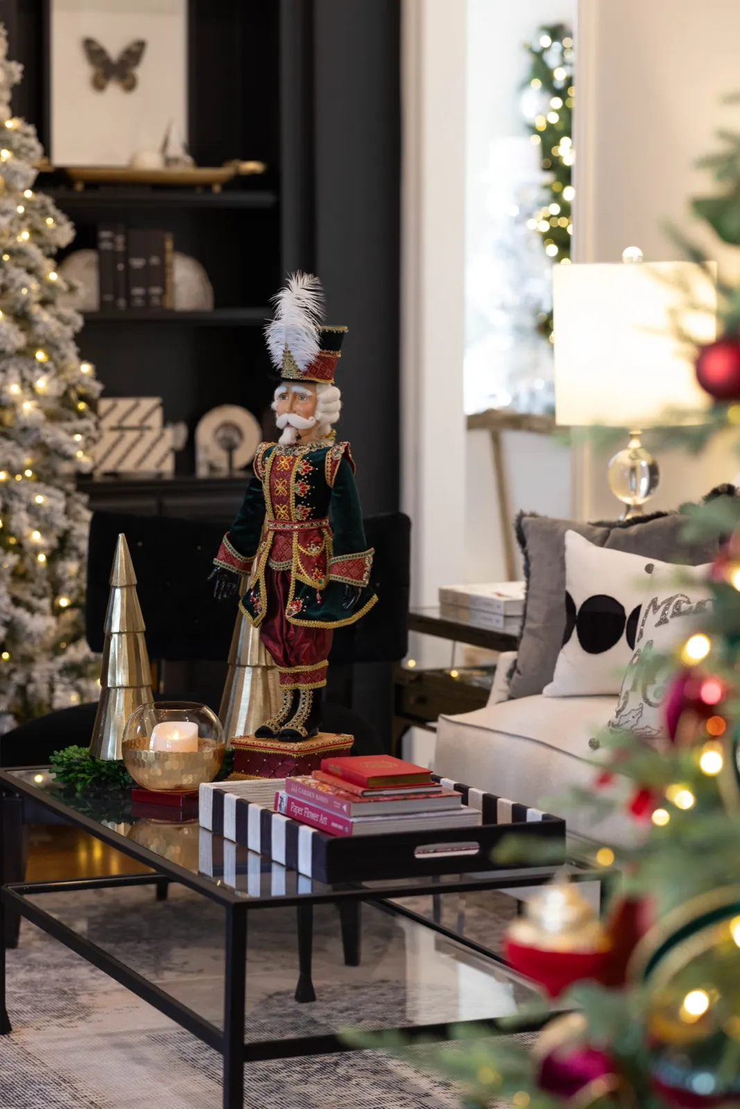 Flocked tree glowing behind a nutcracker styled on a black coffee table.