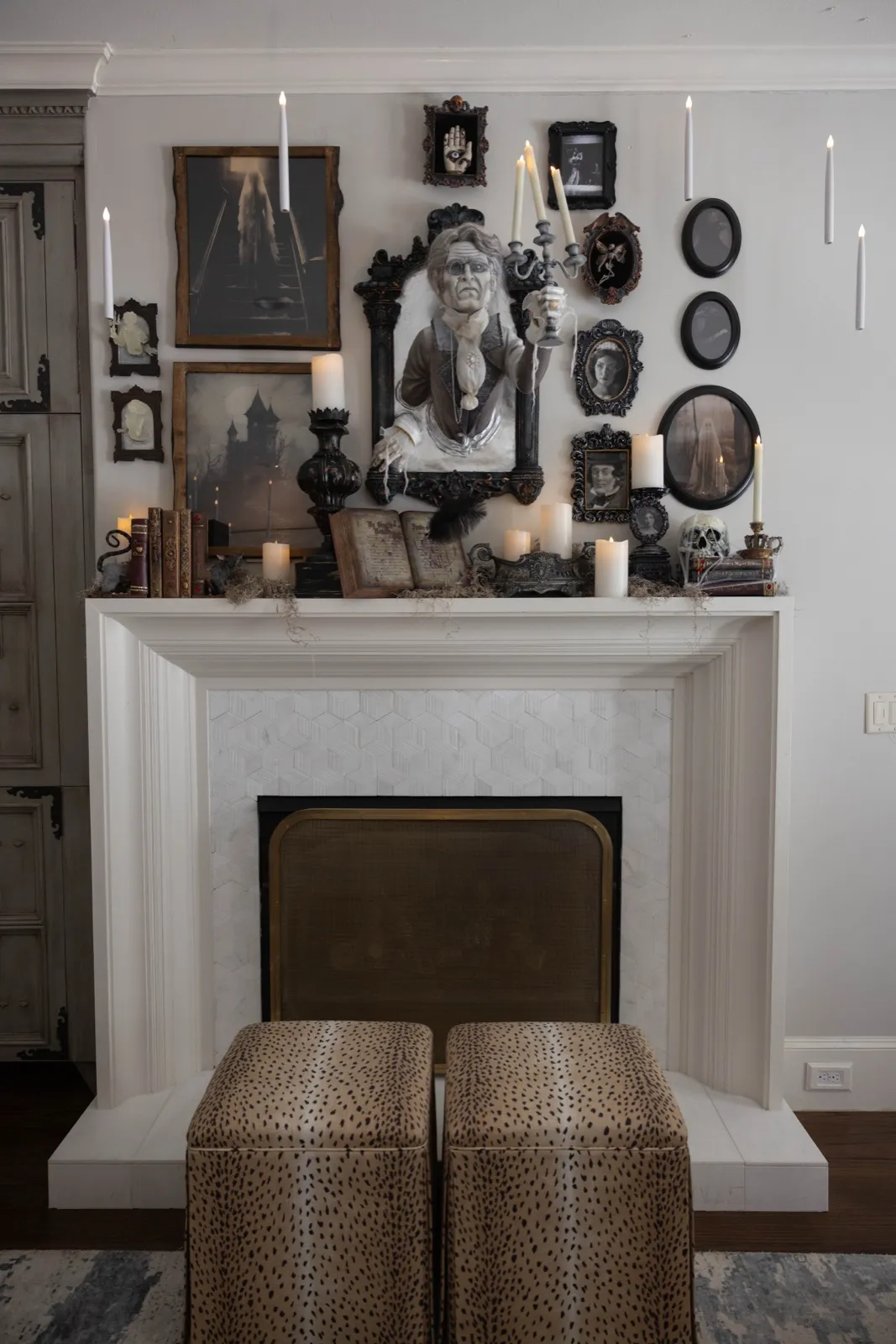 Haunted gallery wall of dark portraits and candles above a white fireplace.