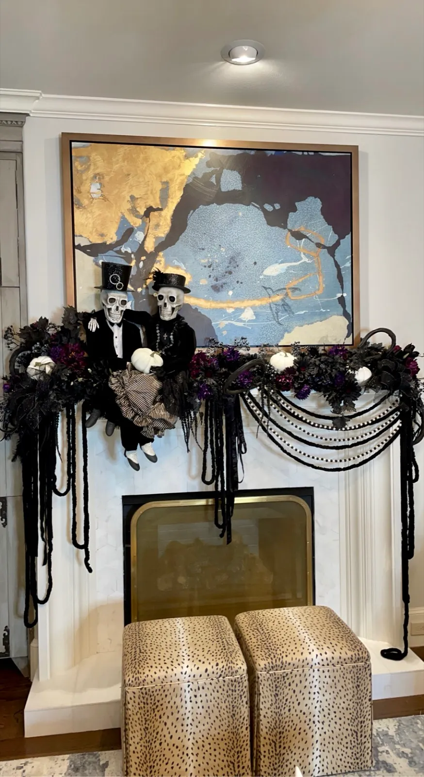 White mantel draped in black chains and beads with skeleton figures and miniature pumpkins.