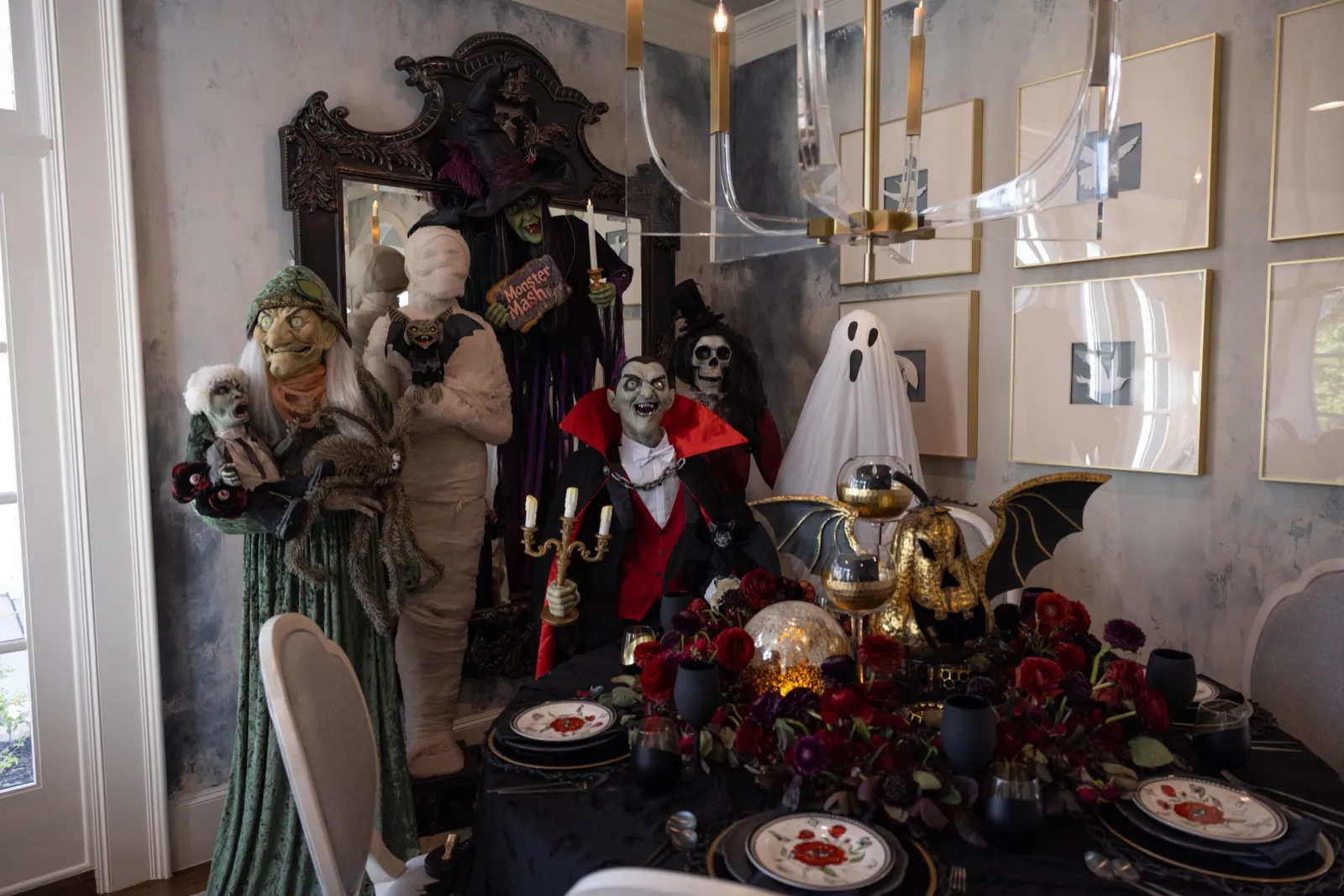 Halloween dining tablescape with a ghost, vampire and monster figures, candelabra and dark florals.