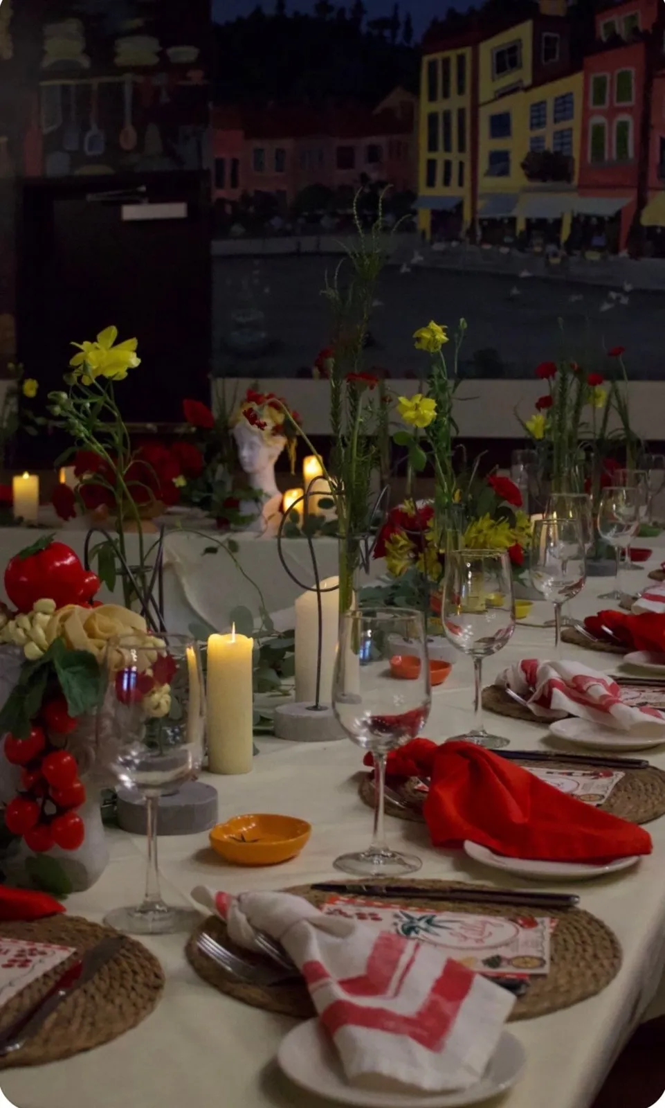 Candlelit Italian dinner tablescape with red napkins and bud vases.